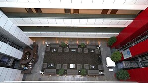 Una terraza en la azotea con varias zonas de estar, un jardín central y vistas de los edificios circundantes.