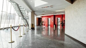 Un vestíbulo amplio con piso pulido, una escalera y paredes rojas.