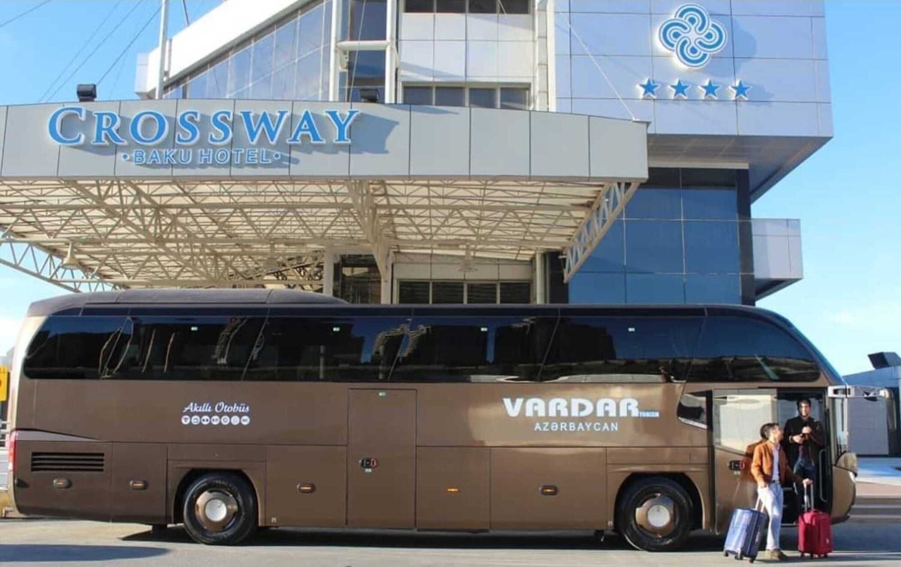 Un autobus arborant les inscriptions « VARDAR AZOR BAYCAN » et « Akulli Otobius » est stationné devant le bâtiment de l’hôtel « CROSSWAY BAKU ».