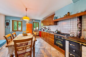 Una cocina con armarios de madera, una estufa y una mesa de comedor con sillas.