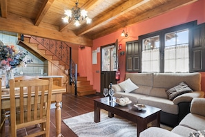 A wooden interior with a staircase, a sofa, a dining table, and a coffee table.