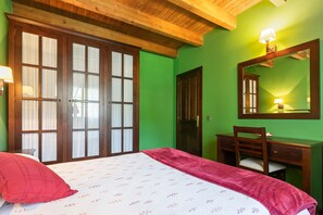Une chambre à coucher comprenant un lit, un bureau, une chaise, un miroir et une armoire.