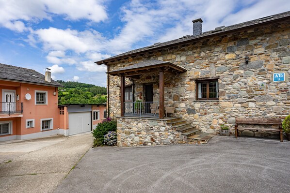 Un bâtiment en pierre doté d’un porche, d’un banc et d’une enseigne indiquant la présence d’un restaurant.