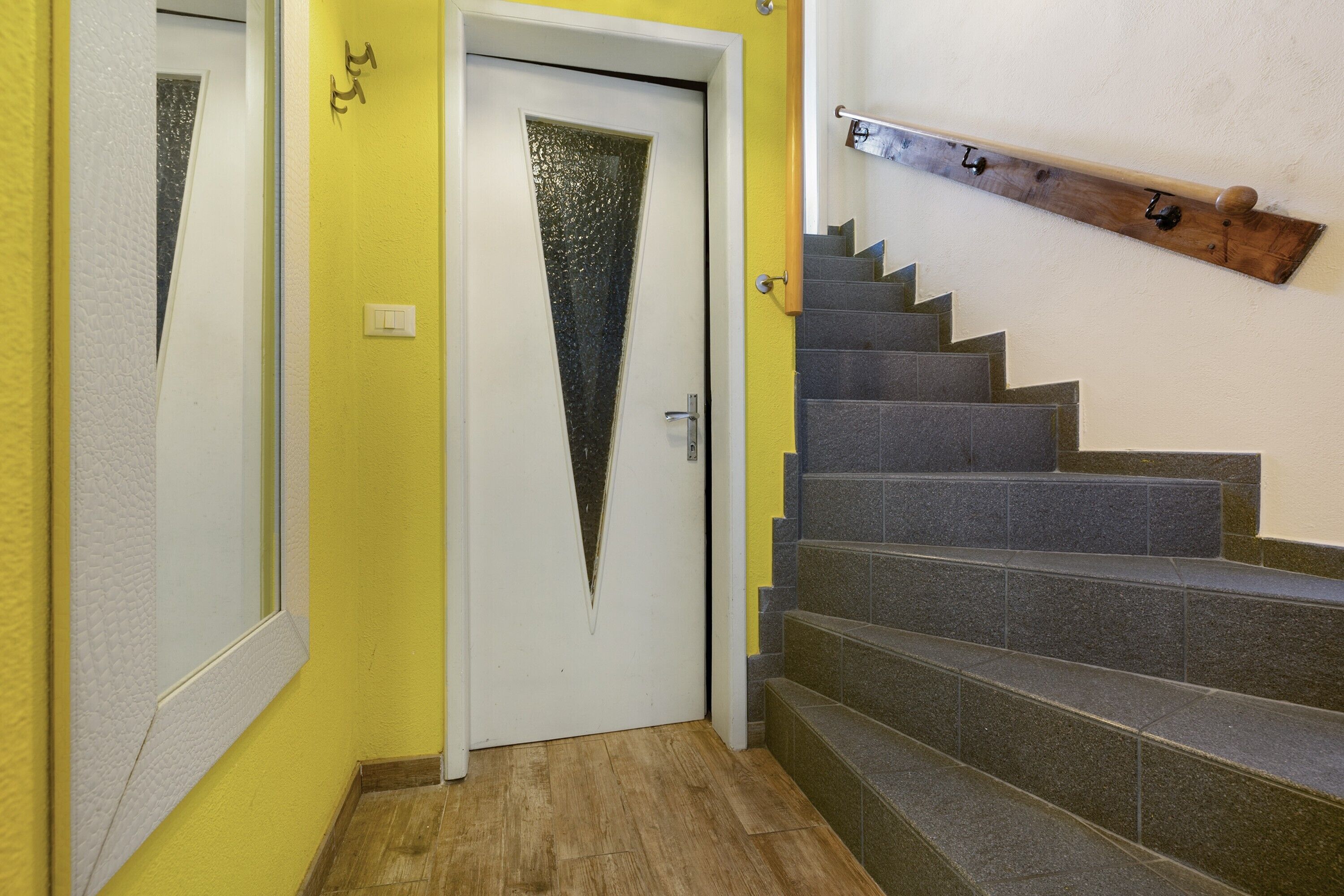 A staircase with a wooden handrail and a door with a frosted glass panel.
