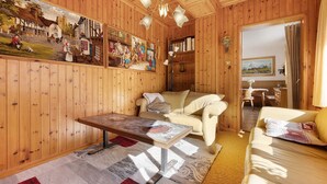 Ein Zimmer mit Holzvertäfelung, einer Couch, einem Couchtisch, einem Gemälde und einem Bücherregal.