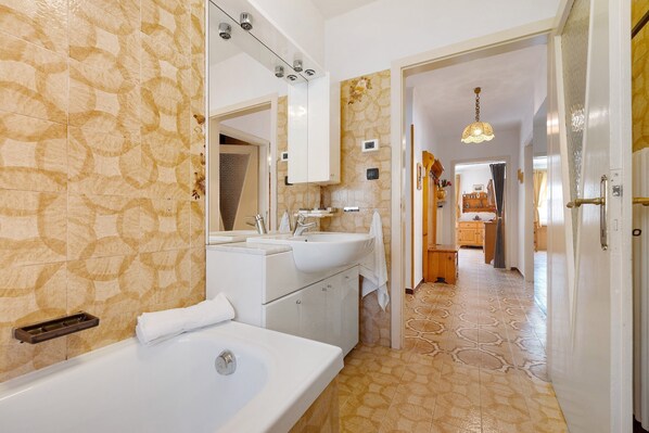 A bathroom with a bathtub, two sinks, a mirror, and a towel rack.