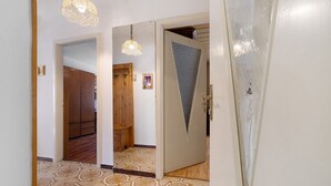 Ein Korridor mit gemustertem Boden, einer Holztür mit geometrischem Dekor und einer hängenden Leuchte.