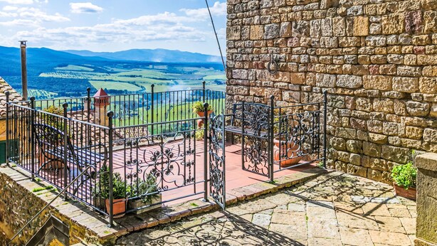 A stone wall with a metal gate and a bench, overlooking a scenic landscape with fields and distant mountains. - Montaleo by Interhome (Casale Marittimo)