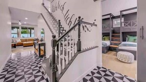 Un escalier avec un revêtement de sol aux motifs géométriques, une rampe d’escalier moderne, et une pièce comprenant un lit et des meubles de rangement.