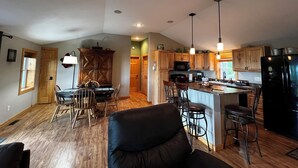 A spacious kitchen with wooden cabinets, a central island with bar stools, and a large refrigerator. - Heaven on Lake Edward  (Nisswa)