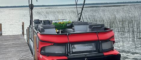 Um veículo Sea-DOO vermelho estacionado em um píer de madeira que se estende sobre a água.
