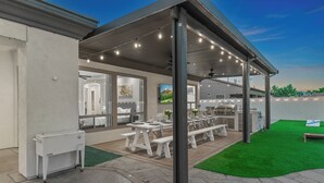 A covered outdoor patio with a dining area, a grill, and a view of the water. - Walk to Stagecoach,incredible gameroom, putting green, bocce, slide, pickleball (Indio)
