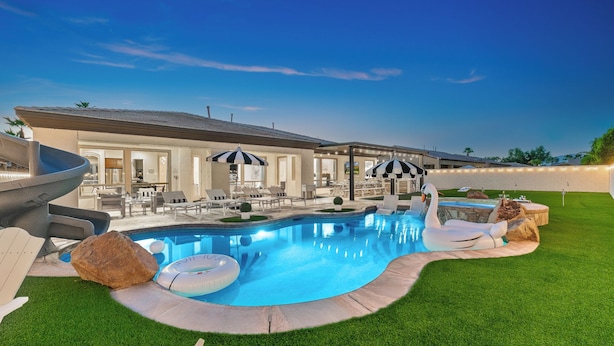 A swimming pool with a swan float, lounge chairs, and umbrellas. - Walk to Stagecoach,incredible gameroom, putting green, bocce, slide, pickleball (Indio)