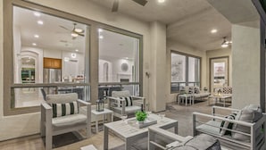 A spacious living area with a modern design, featuring a large window, a ceiling fan, and a dining area with a table and chairs. - Walk to Stagecoach,incredible gameroom, putting green, bocce, slide, pickleball (Indio)