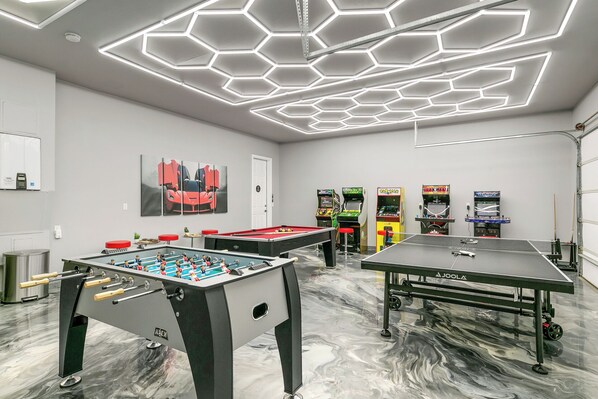 A recreational room with foosball tables, pool tables, and arcade games.