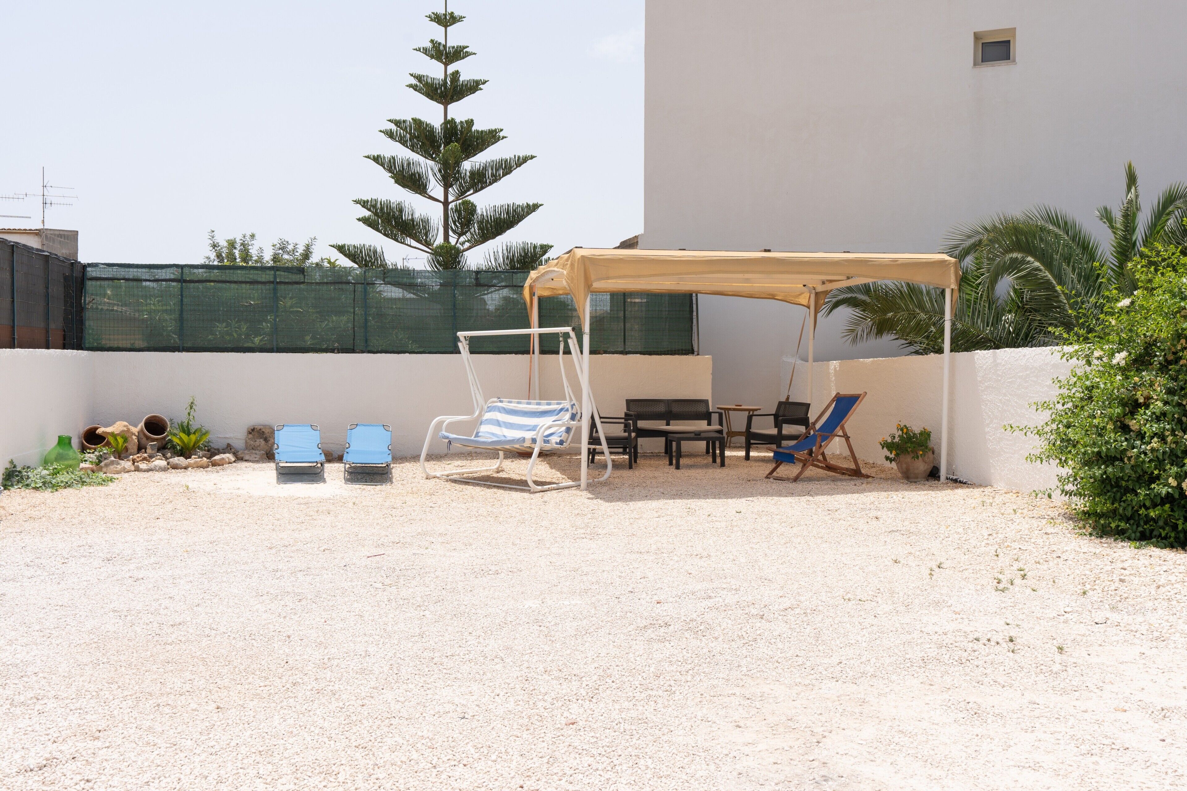 An outdoor seating area with a canopy, two blue lounge chairs, and a table.