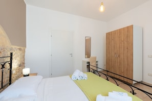 A bedroom with a bed, a wooden wardrobe, a desk, and a chair.