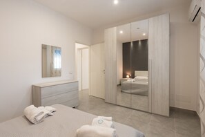 Een moderne slaapkamer met een bed, een dressoir, een kledingkast en een spiegel.