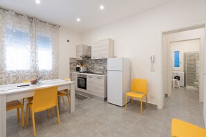 Een moderne keuken met een eethoek, een wasmachine en een kleine badkamer, zichtbaar door een open deur.