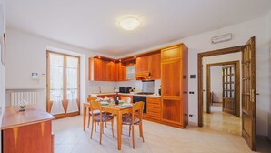 Una cucina moderna con mobili in legno, un tavolo da pranzo con sedie e un forno integrato.
