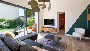 En moderne stue med sofa, sofabord, fjernsyn og et spiseområde med en stol.