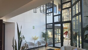 En modern entréhall med en receptionsdisk, en sittgrupp och stora fönster med utsikt över gatan.