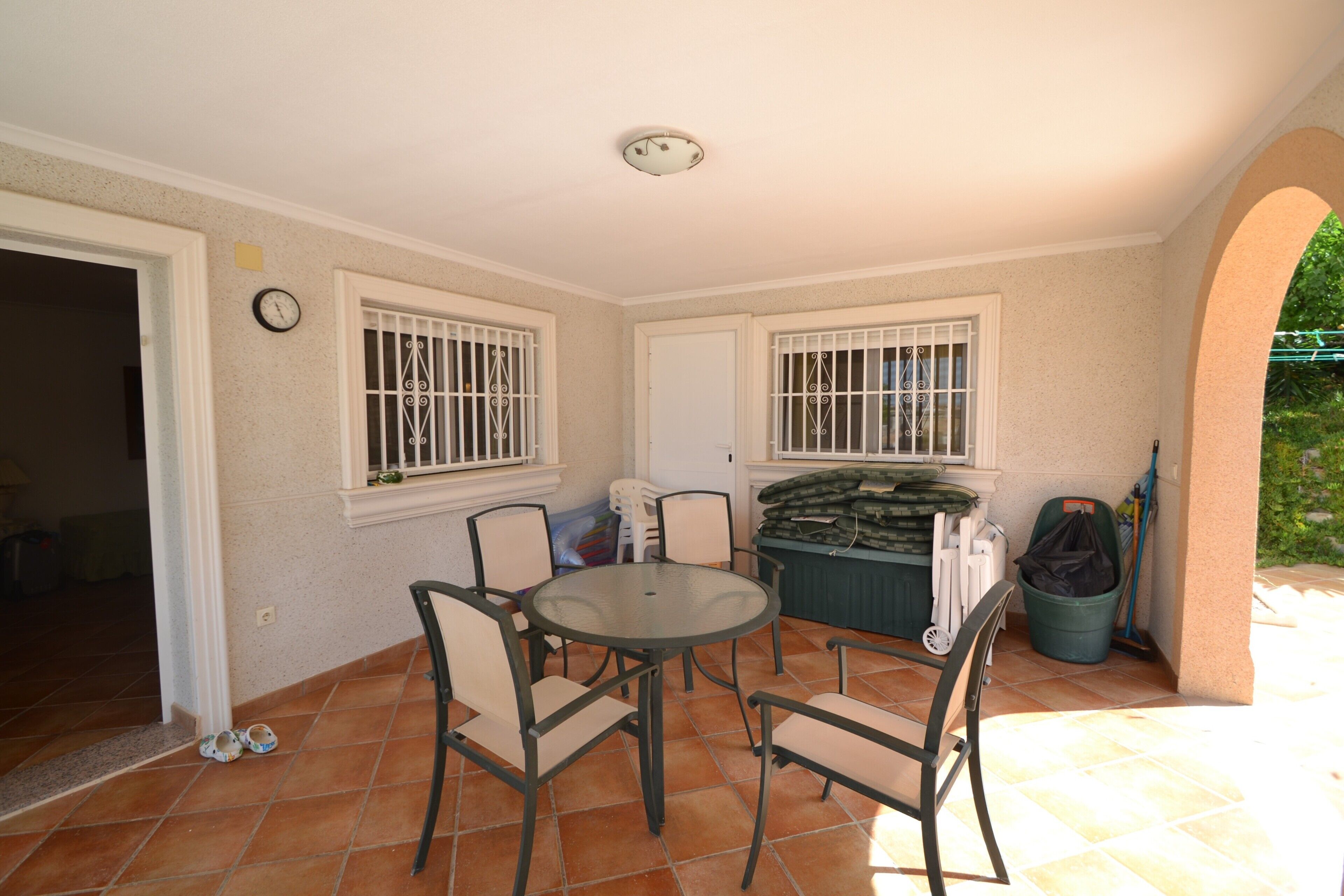 A patio area with a round table and chairs, a door, and windows with bars.