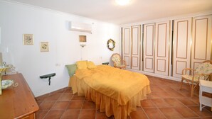A bedroom with a bed, a chair, a small table, a shelf, and a wardrobe. - Villa 'Casa Papa' with Private Pool, Private Terrace and Wi-Fi (San Fulgencio)