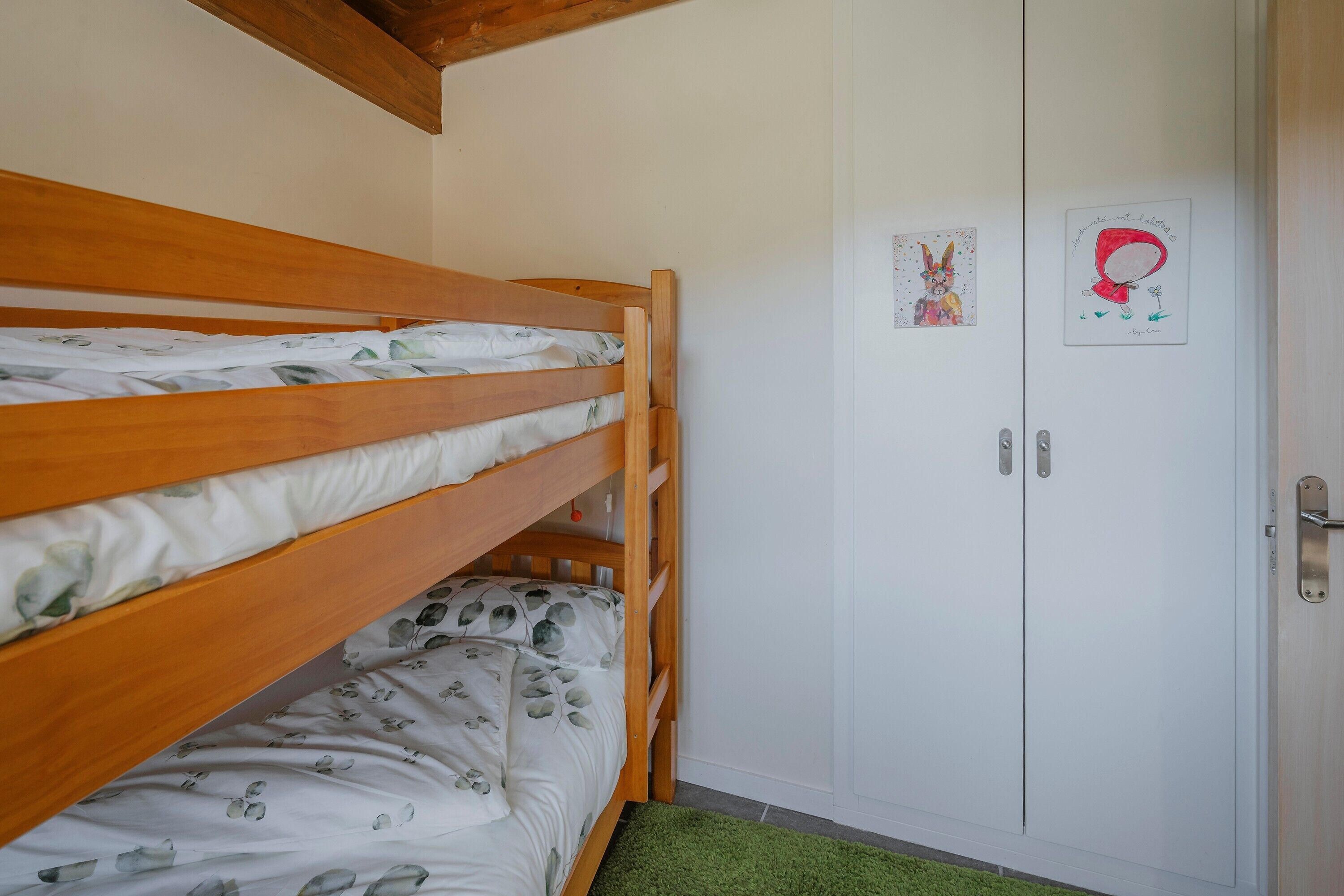 Habitación con literas, armario y dos adornos de pared.