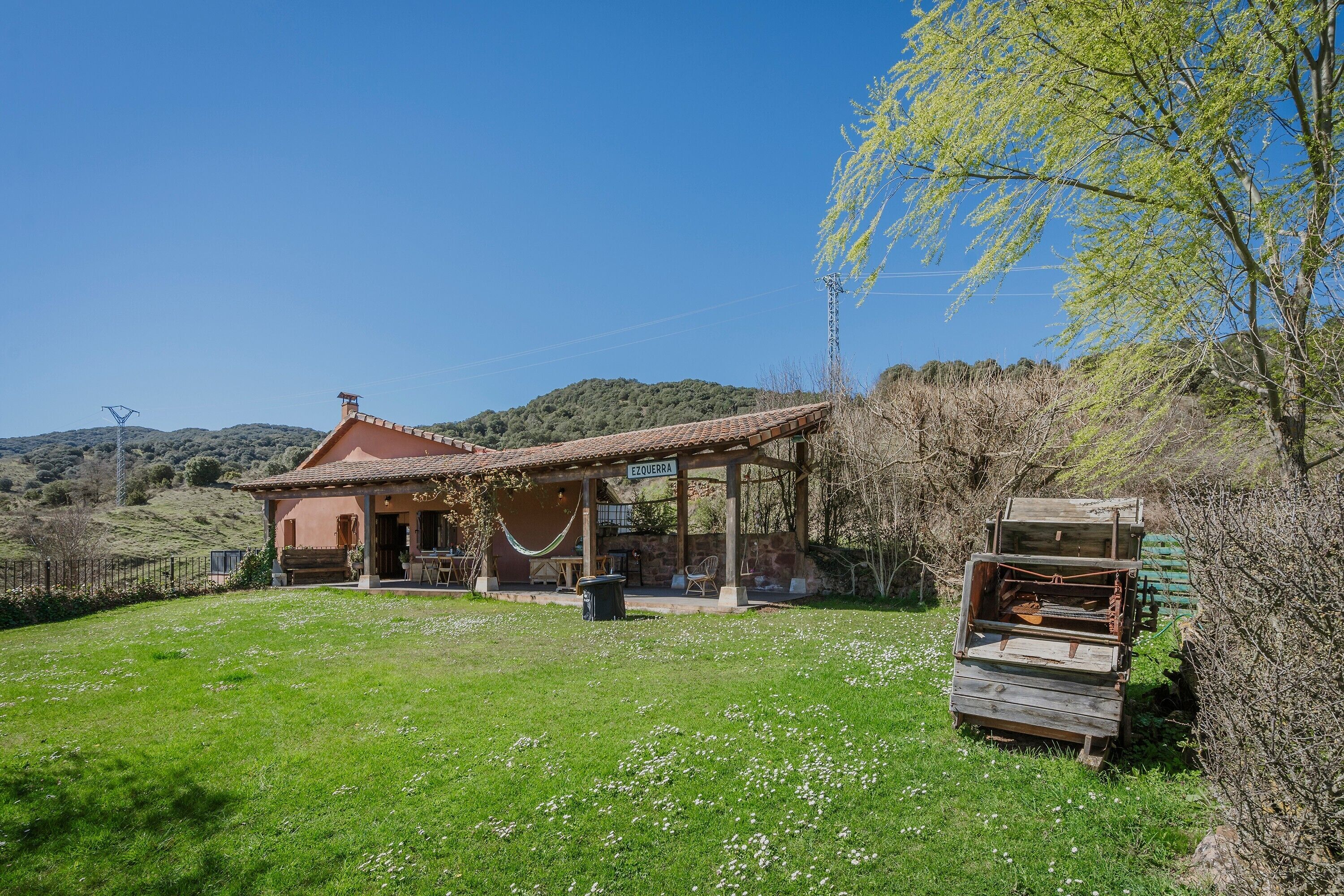 A rustic house with a tiled roof, a covered patio, and a grassy yard.