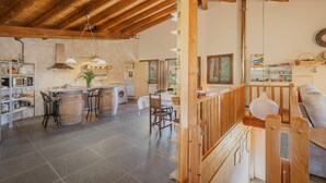 Une cuisine spacieuse avec des poutres en bois, un coin repas avec une table et des chaises, et une vue sur l’extérieur.