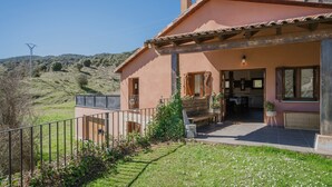 Une maison avec un patio, un jardin et une vue sur les collines.