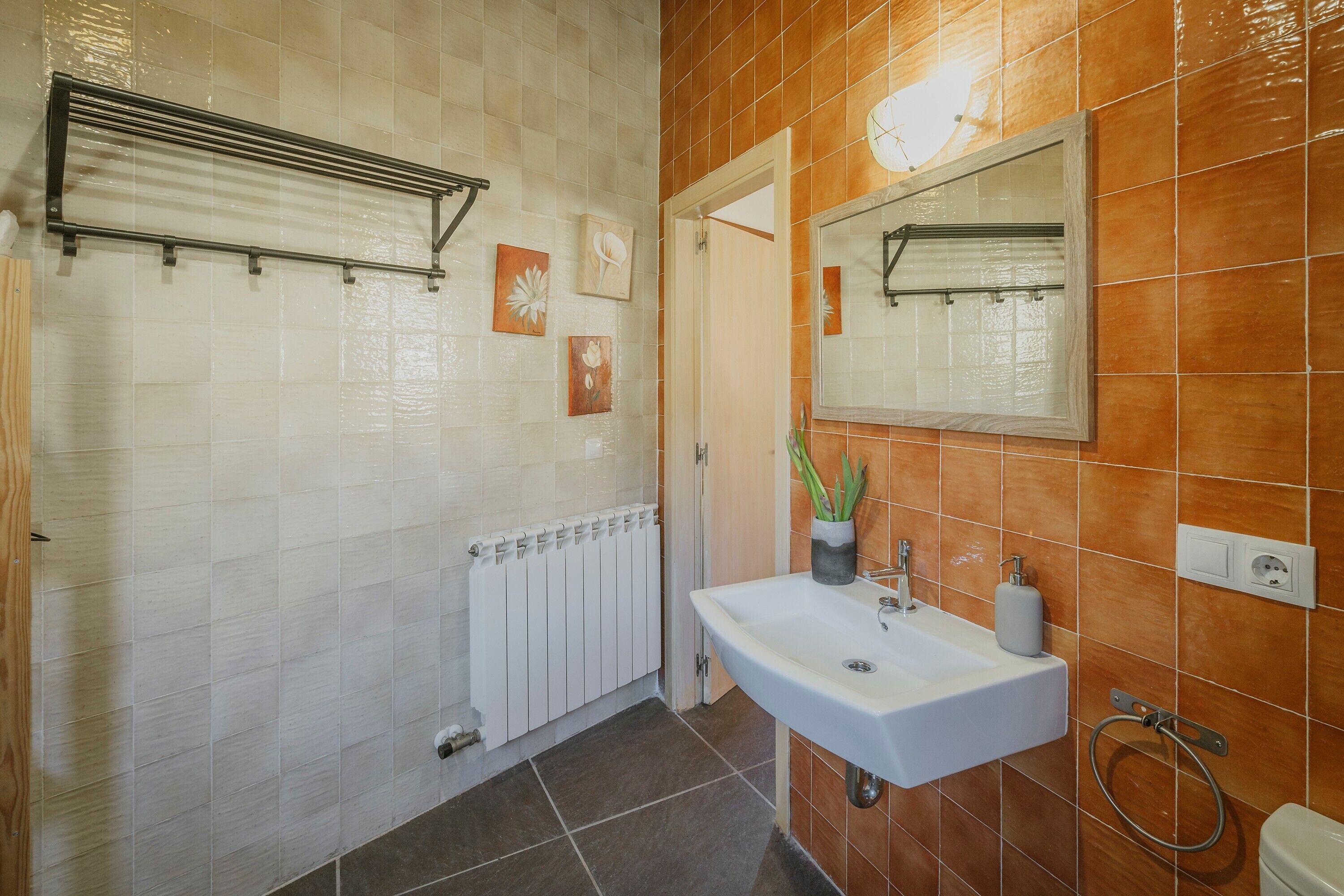 Une salle de bain avec un lavabo blanc, un miroir, un porte-serviettes et un radiateur.