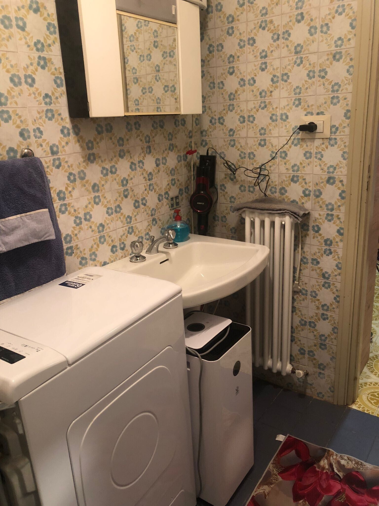 A laundry area with a washing machine, a drying rack, and a sink.