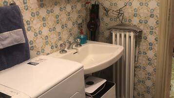 A laundry area with a washing machine, a drying rack, and a sink.