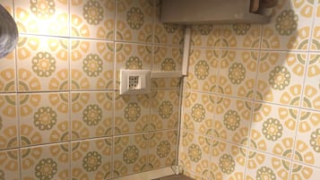 Une cuisine dotée d’une plaque de cuisson à induction noire, d’une hotte aspirante et de carreaux aux motifs jaunes et verts.