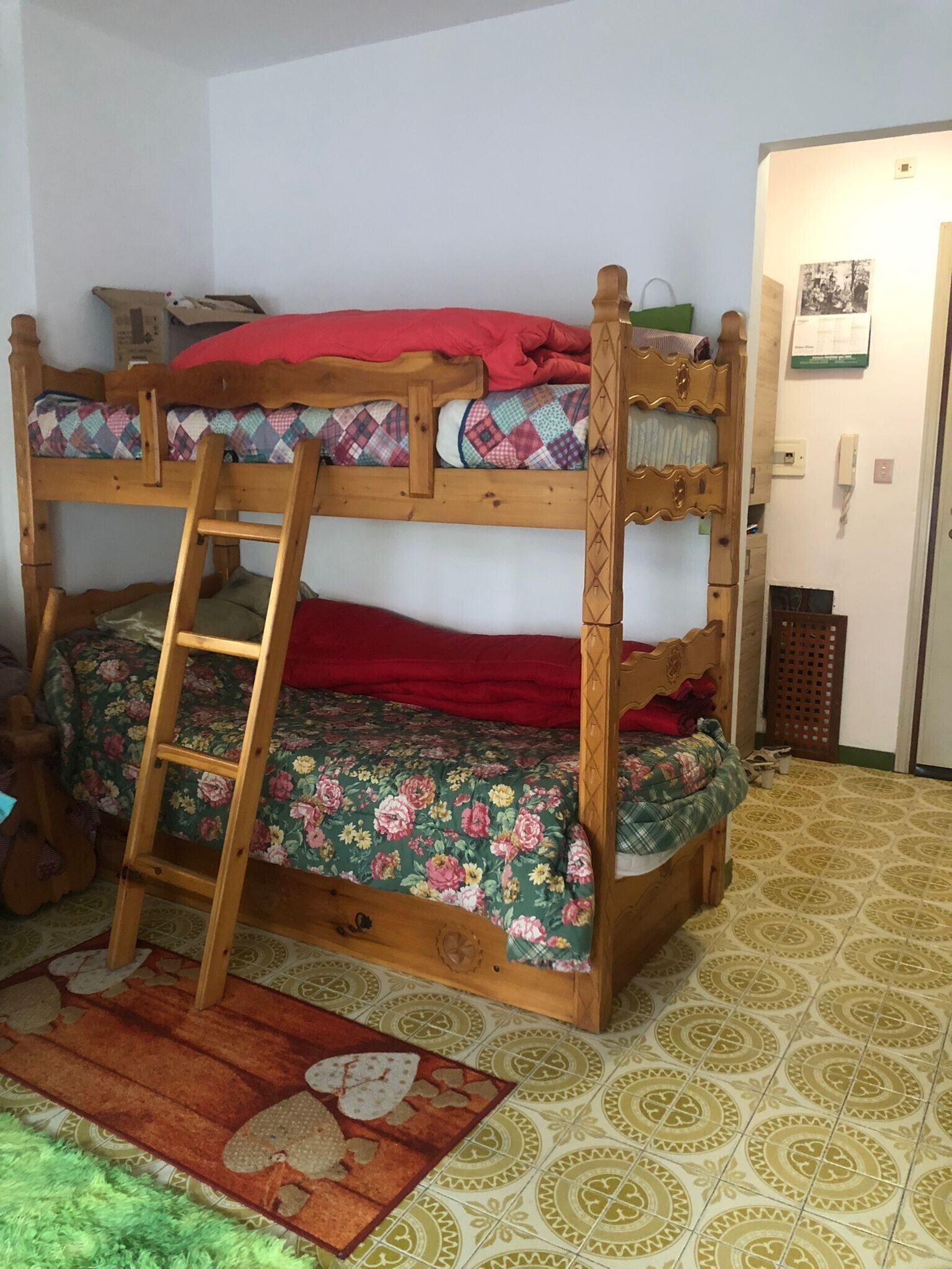 Una cama litera con escalera, una colcha estampada y una alfombra con diseño.