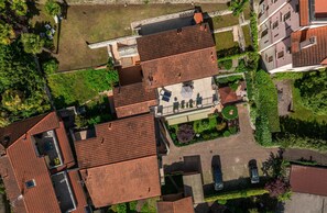 Luchtbeeld van een woonwijk met rode pannendaken, een centraal binnenhof met zitplaatsen en omliggend groen.