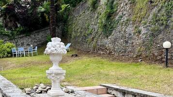 A stone fountain in a garden with steps leading up to a seating area.