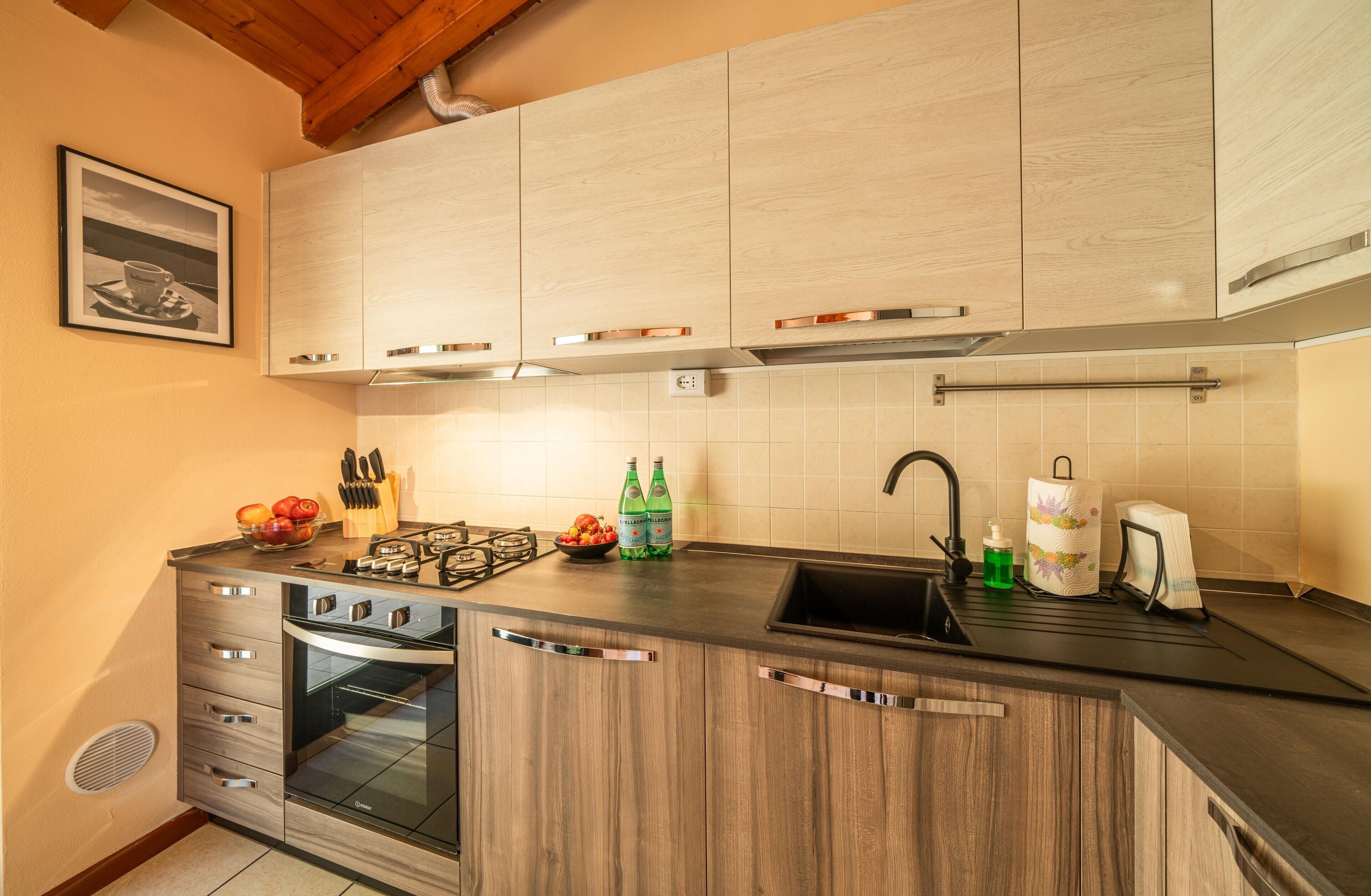 Eine moderne Küche mit Holzausstattung, einem eingebauten Backofen, einer Spüle und einer Arbeitsplatte mit diversen Gegenständen.
