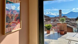 Une chambre avec vue sur un village, un tableau encadré au mur et un balcon agrémenté de plantes en pot.