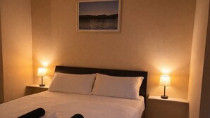 Une chambre d’hôtel avec un lit, deux lampes de chevet, un tableau encadré au mur et des serviettes sur le lit.