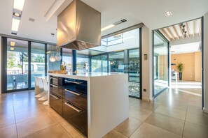 Una cocina moderna con una isla central, electrodomésticos integrados y ventanas amplias.