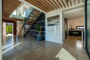 Un interior moderno con una escalera, un cuadro grande y una zona de cocina.