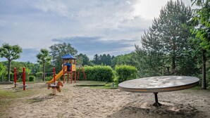 Un parque infantil con un tobogán, estructuras para escalar y un arenero.