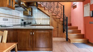 Eine Küche mit Holzausbau, einer Granitabdeckung und einer Treppe mit schmiedeeisernem Geländer.