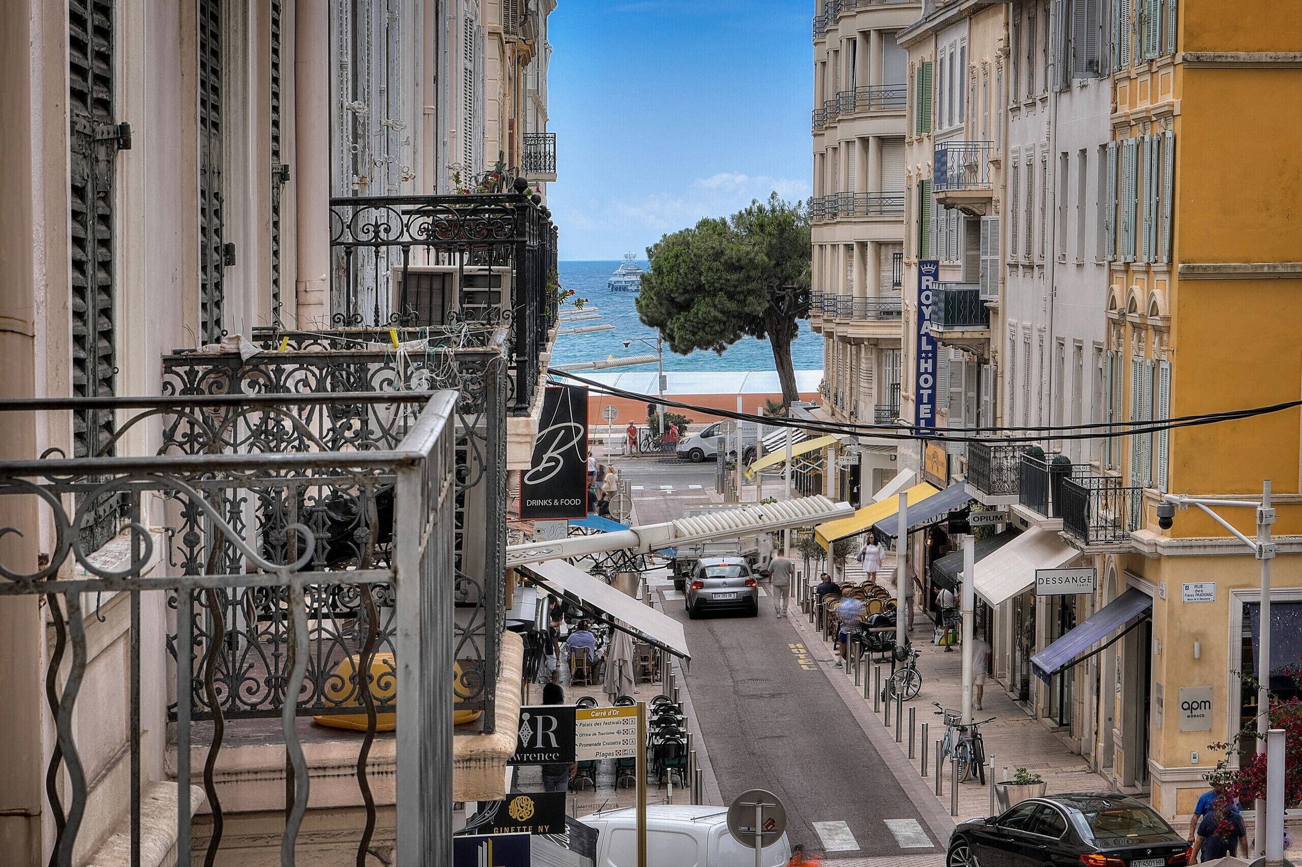 Una vista di una strada con un edificio con la scritta 'Royal Hotel' e un cartello che indica 'Drinks & Food' nelle vicinanze.