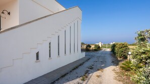 A white building with a gravel path, a gate, and a clear blue sky. - Apartment 'Muma 4' with Shared Terrace, Wi-Fi and Air Conditioning (otranto)