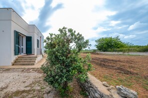A modern building with a stone wall, a small tree, and a clear sky.