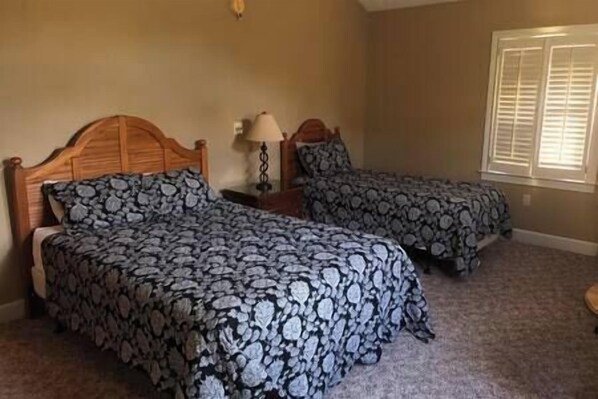 A bedroom with two beds, a nightstand, a lamp, and a window with blinds. - The Lake House on Cherokee Ridge Golf Course 2nd floor (Cherokee Ridge)